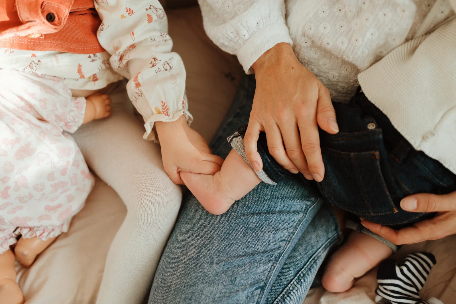 Détail des mains d’une famille pendant une séance photo nouveau-né à domicile