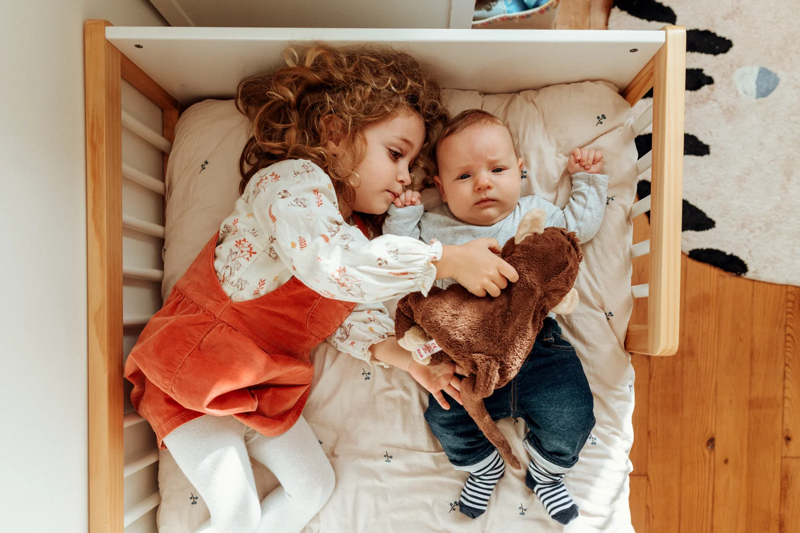 Grande sœur allongée avec son petit frère pendant une séance photo famille avec bébé