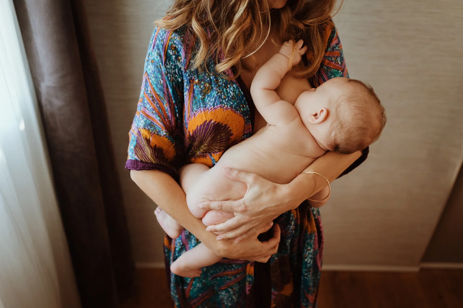 Bébé blotti contre sa maman pendant une séance photo naissance à domicile