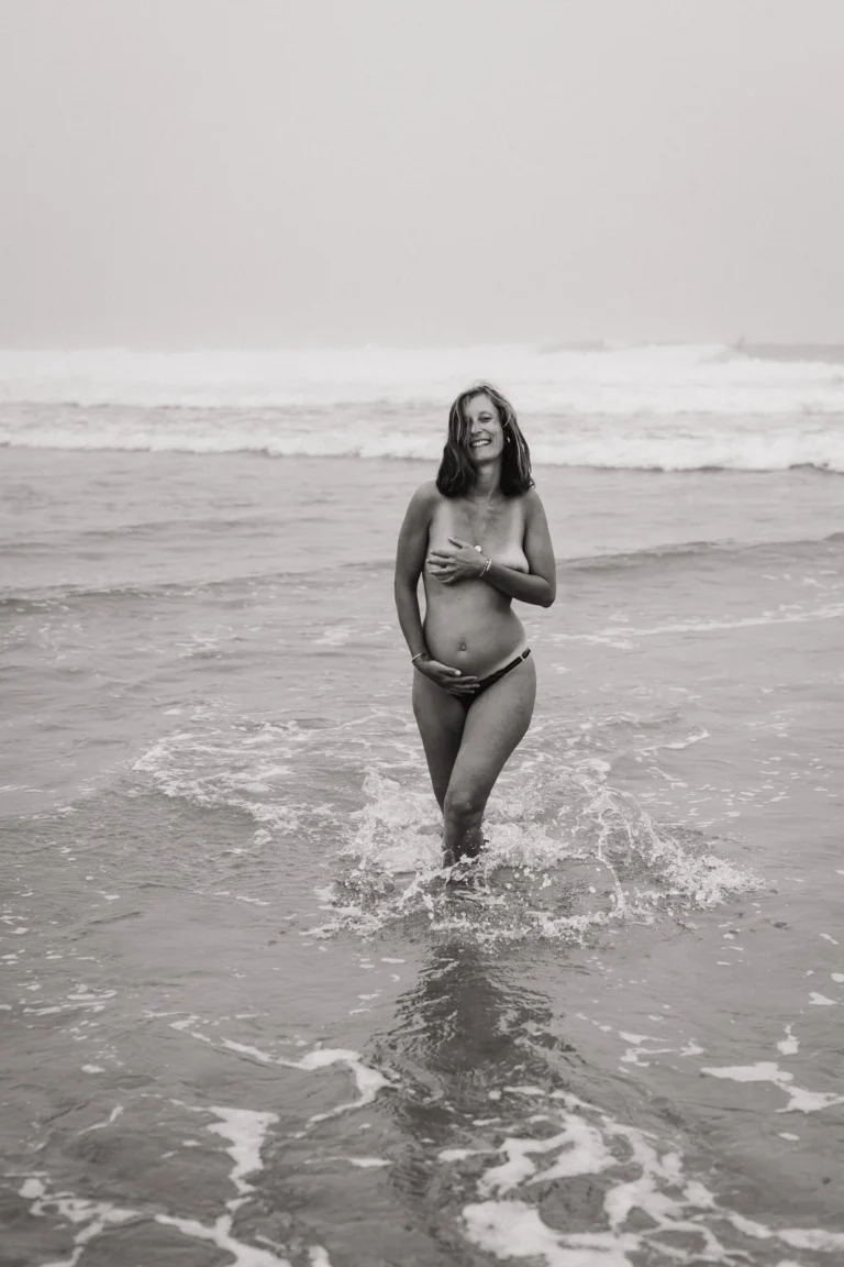 Femme enceinte lors d’une séance photo grossesse à Capbreton, marchant au bord de l’océan (noir et blanc).