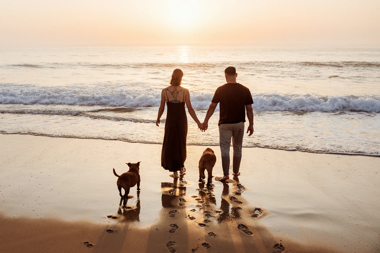 Couple avec leurs chiens face à l’océan pendant une séance photo dans les Landes
