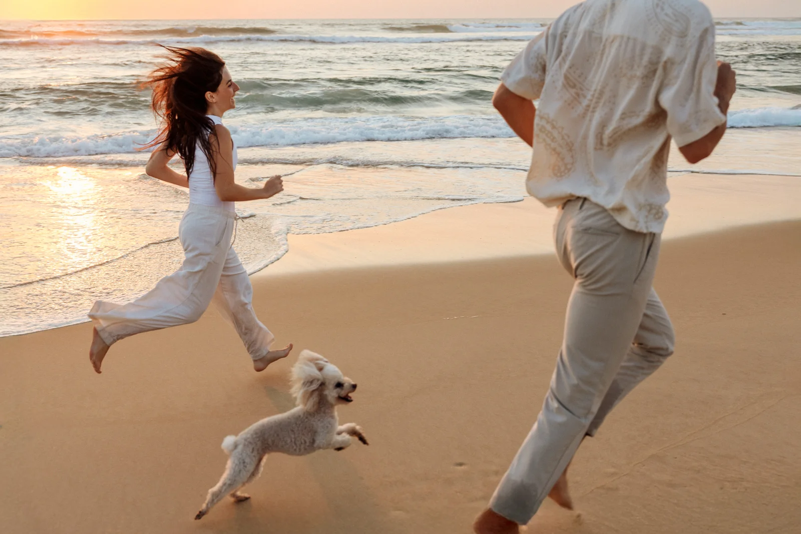 Couple courant sur la plage avec leur chien pendant une séance photo lifestyle dans les Landes
