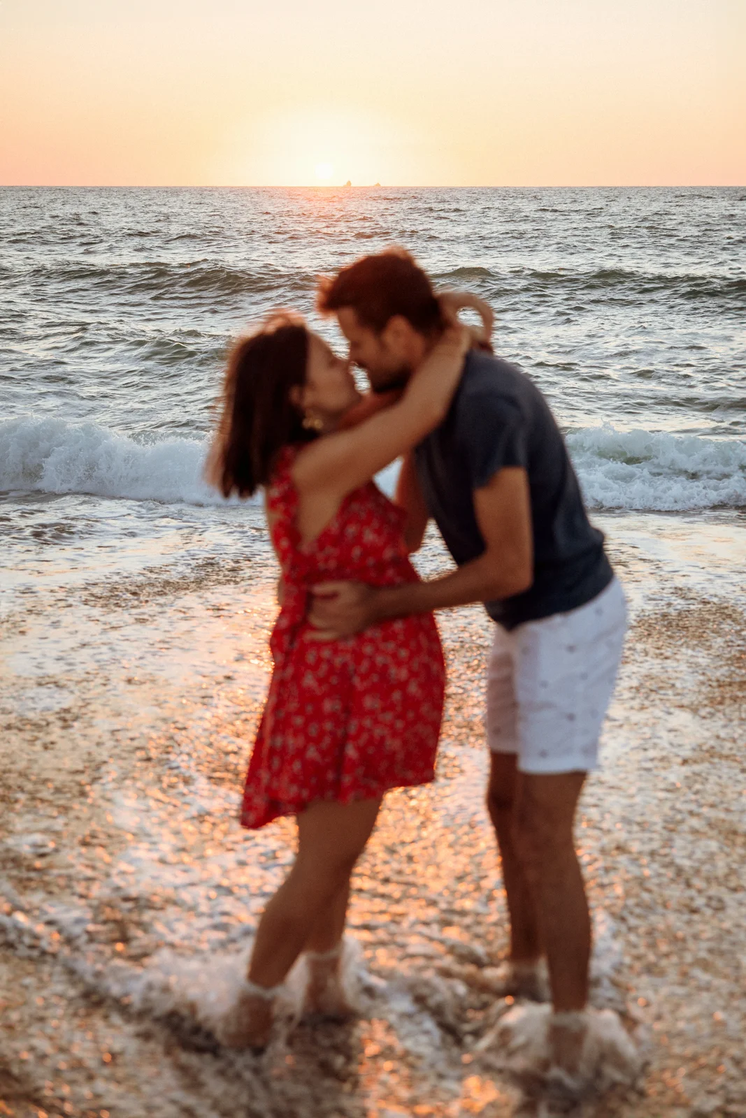 Couple s’embrassant dans les vagues au coucher du soleil sur une plage des Landes