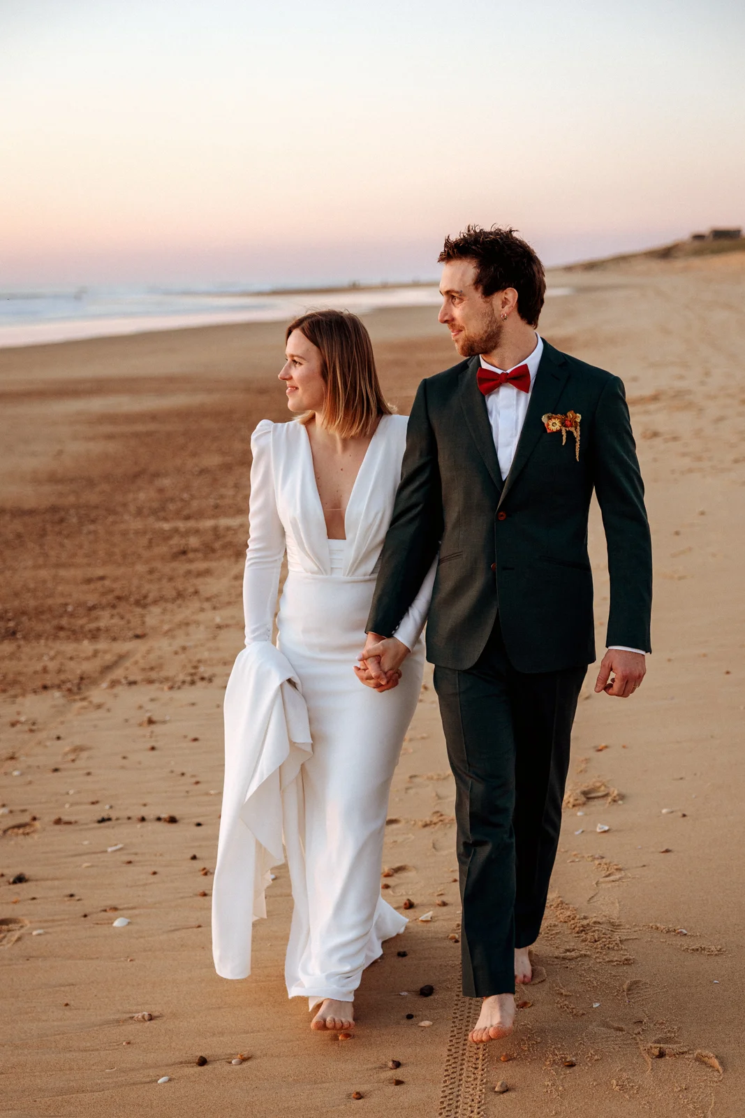 Couple marchant pieds nus sur la plage après leur mariage dans les Landes