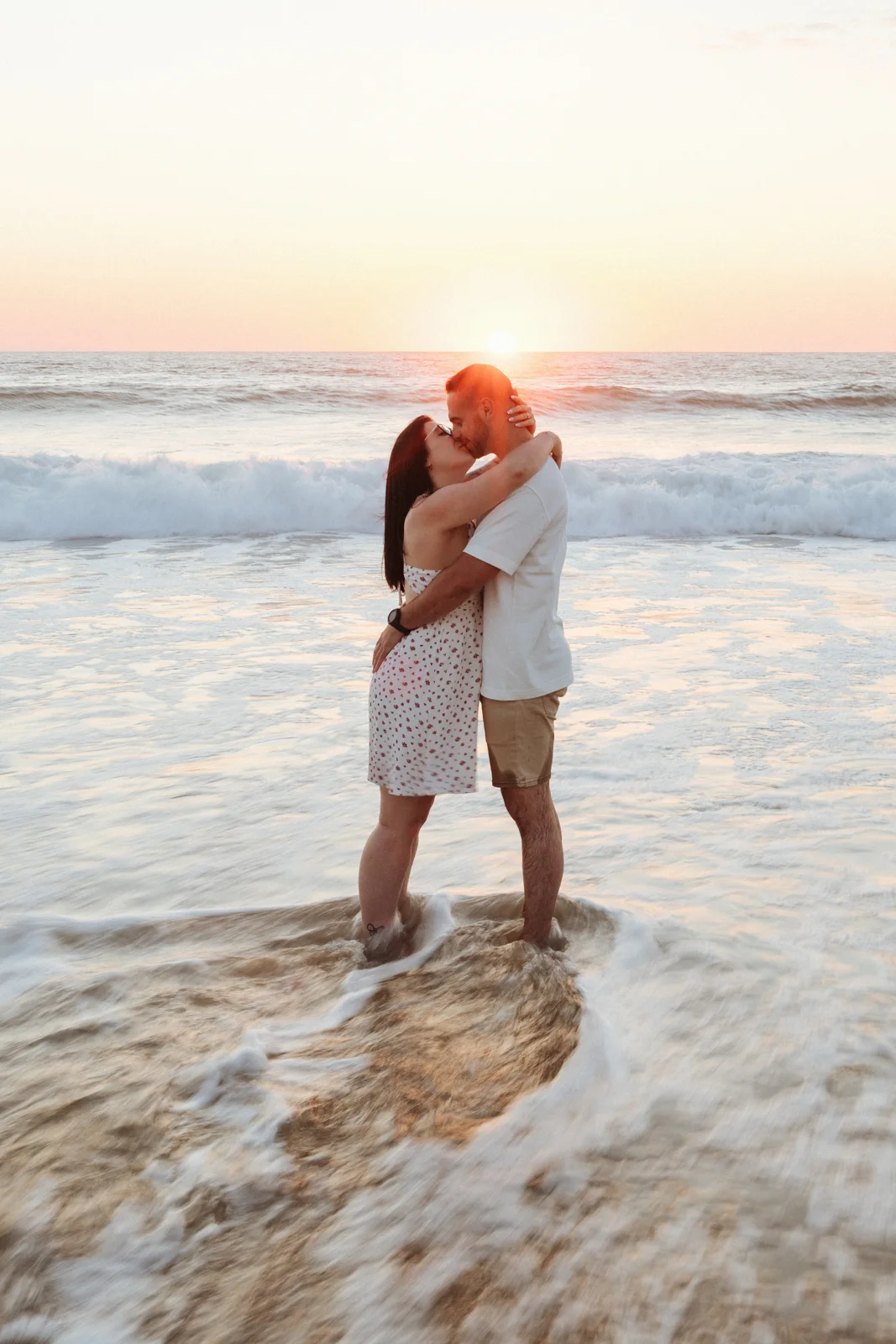 Couple enlacé dans les vagues au coucher du soleil pendant une séance photo couple dans les Landes