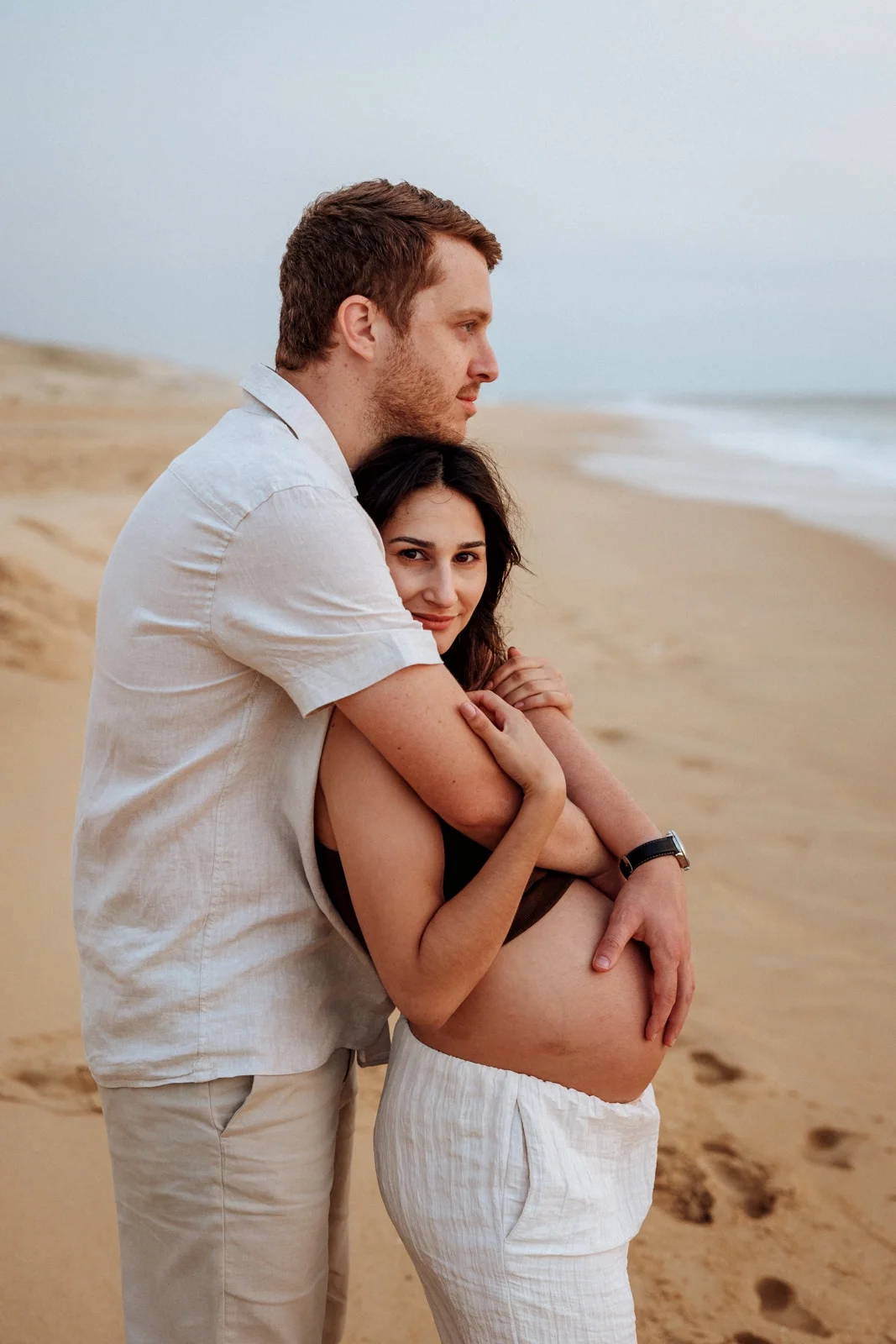 Couple enlacé sur la plage lors d’une séance grossesse dans les Landes