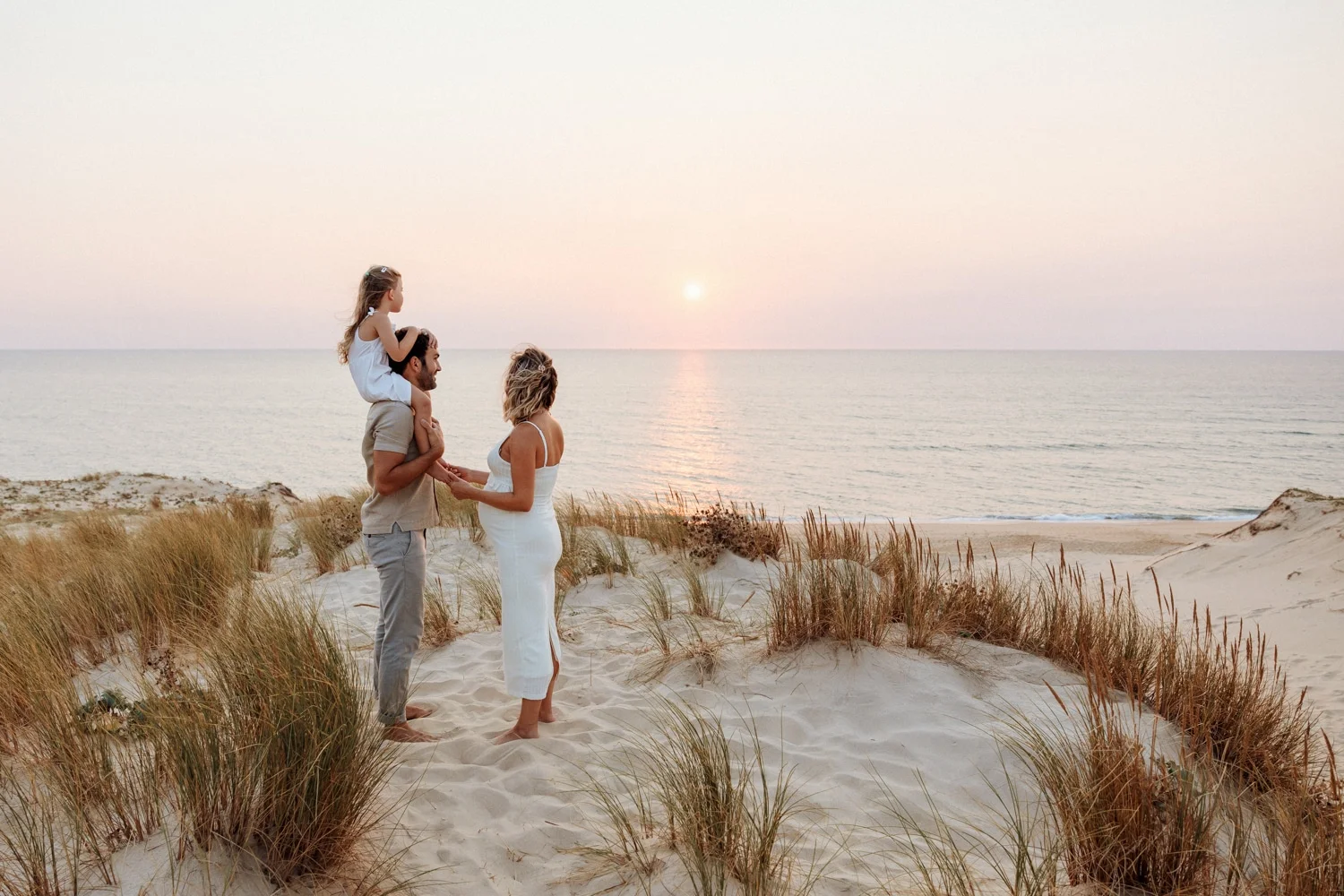 Famille attendant un bébé sur les dunes des Landes au coucher du soleil