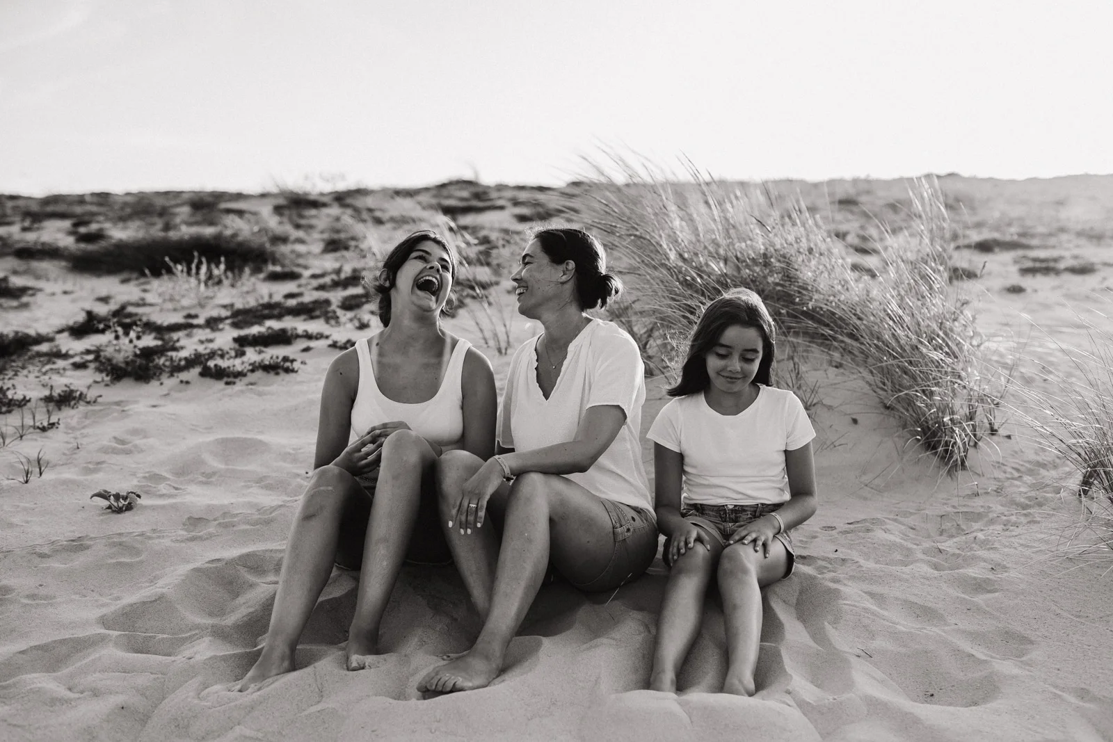 famille assise dans les dunes lors d’une séance photo famille dans les Landes en noir et blanc