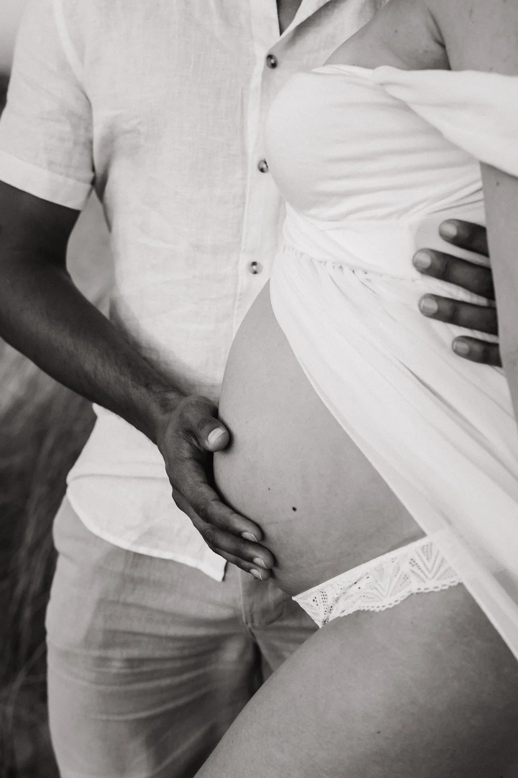 Photo de grossesse en couple à Capbreton, détail du ventre sur la plage.