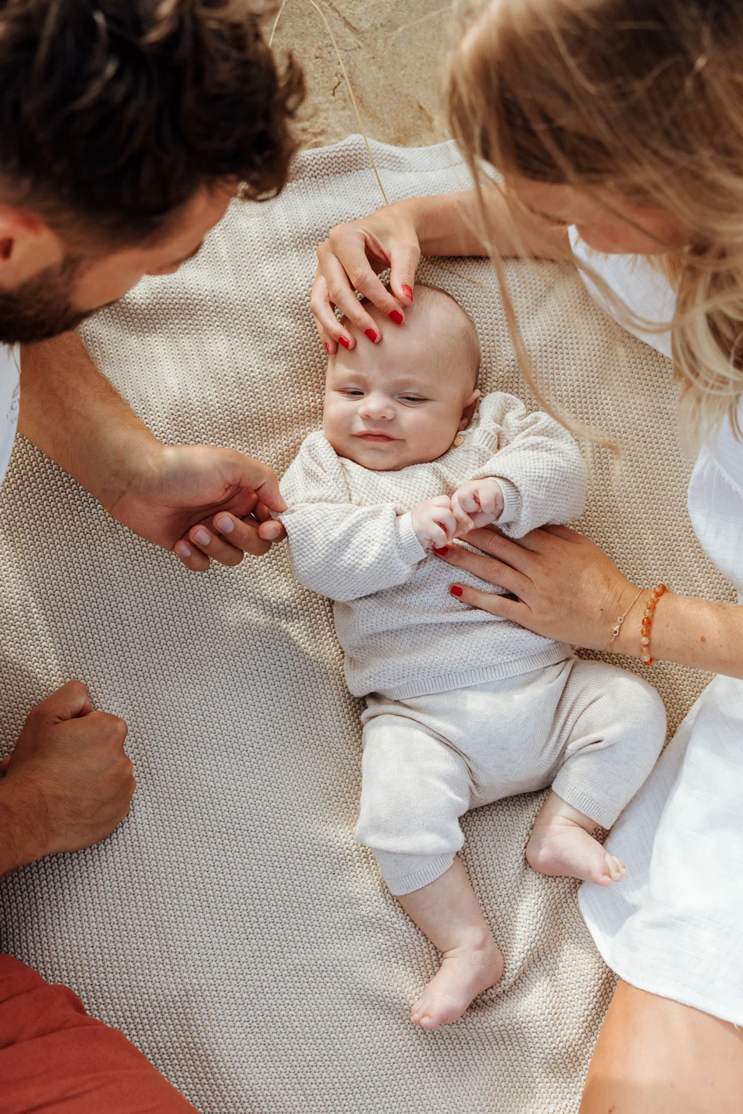 bébé entouré des mains de ses parents lors d’une séance photo en famille dans les Landes