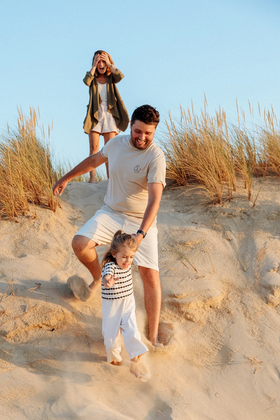 famille courant dans les dunes avec un enfant lors d’une séance photo naturelle dans les Landes