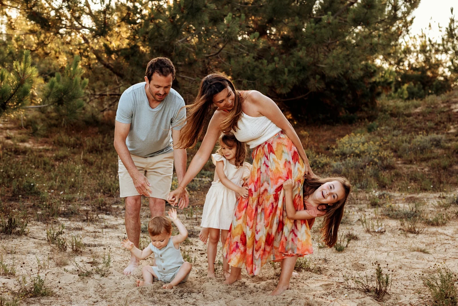 parents et enfants jouant ensemble dans les pins lors d’une séance photo famille dans les Landes
