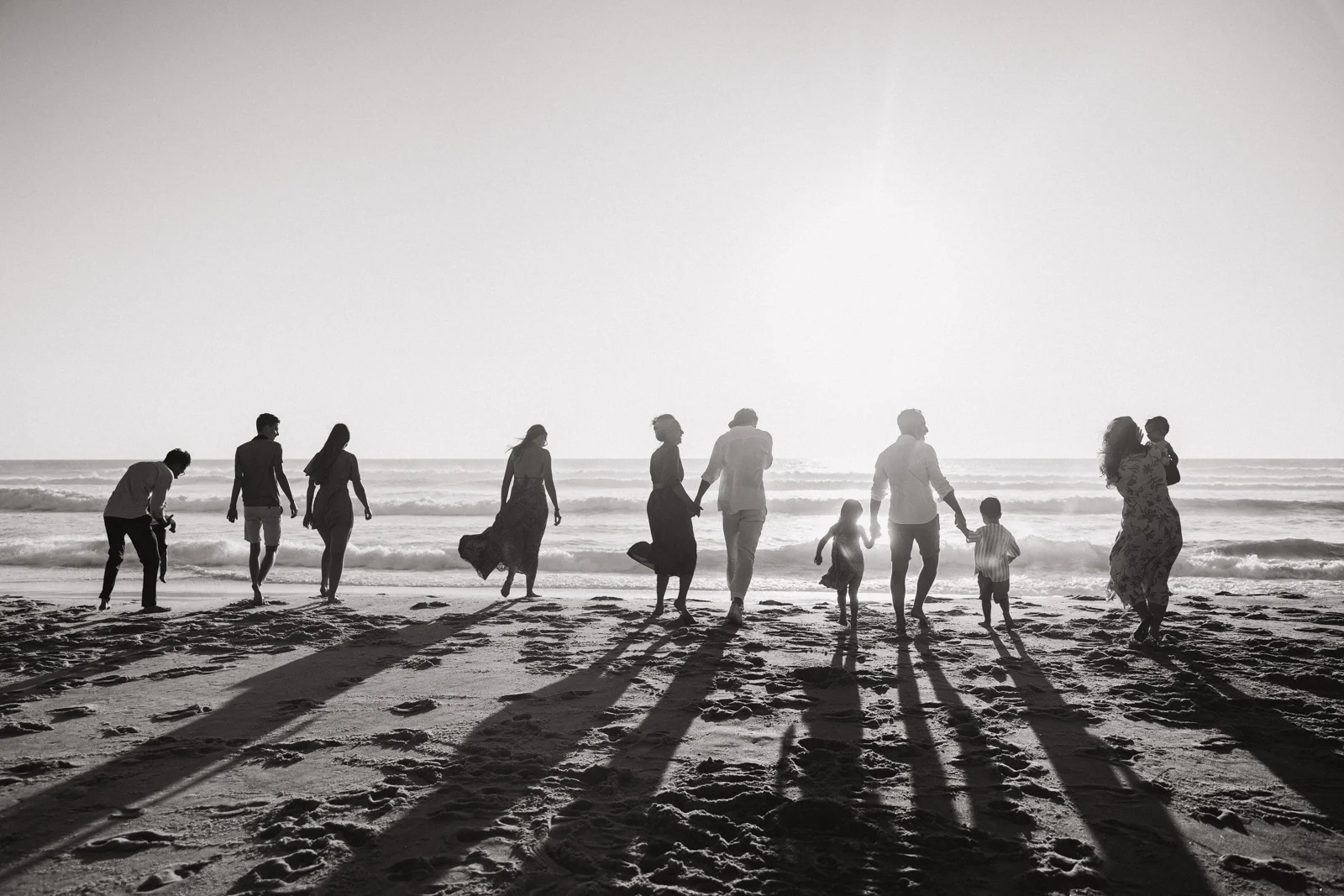famille nombreuse marchant sur la plage face à l’océan en noir et blanc lors d’une séance photo dans les Landes