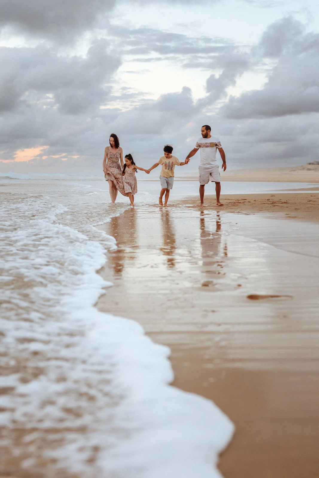 famille marchant sur la plage avec reflet sur le sable mouillé lors d’une séance photo dans les Landes