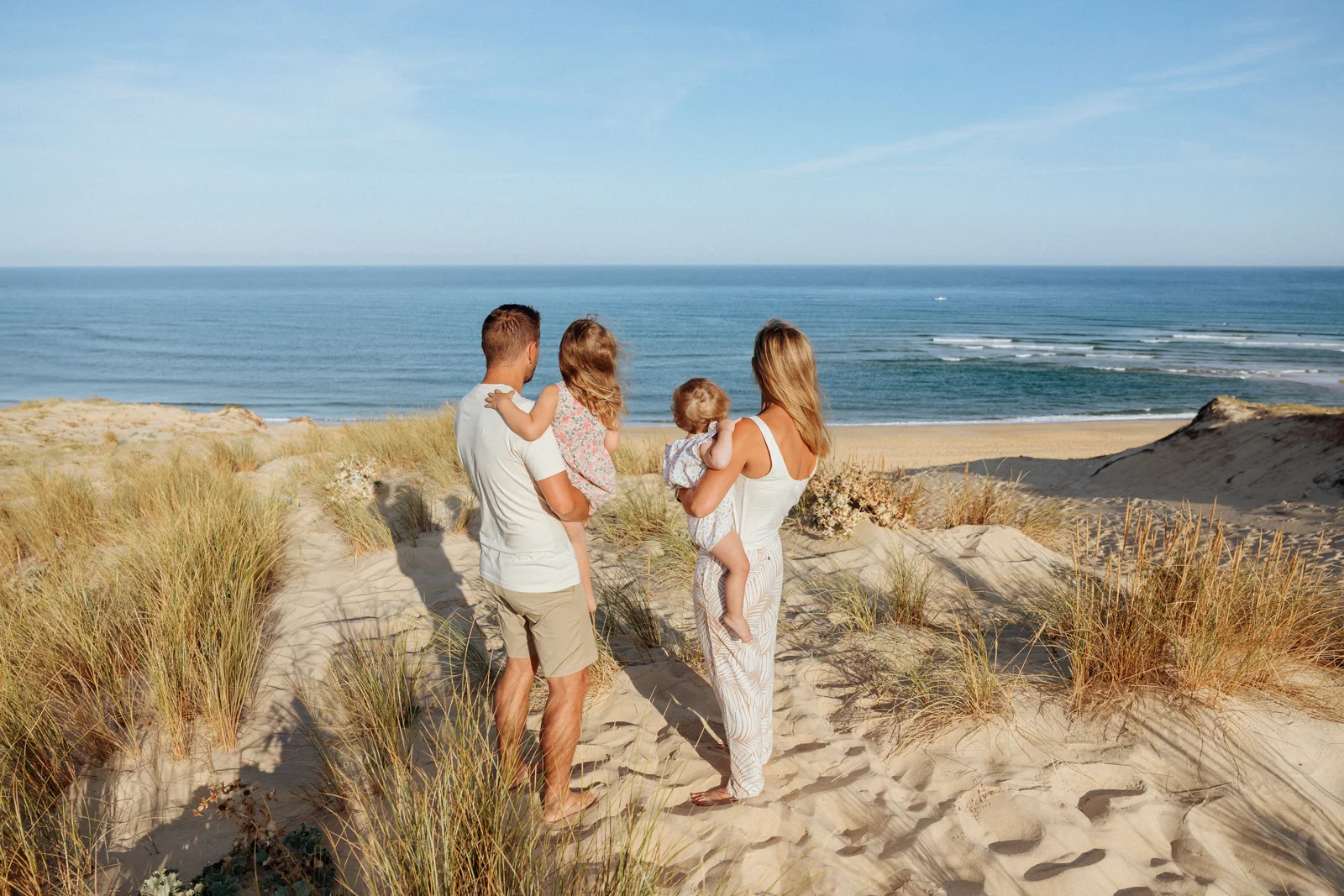 famille avec deux enfants face à l’océan sur les dunes lors d’une séance photo pendant des vacances dans les Landes