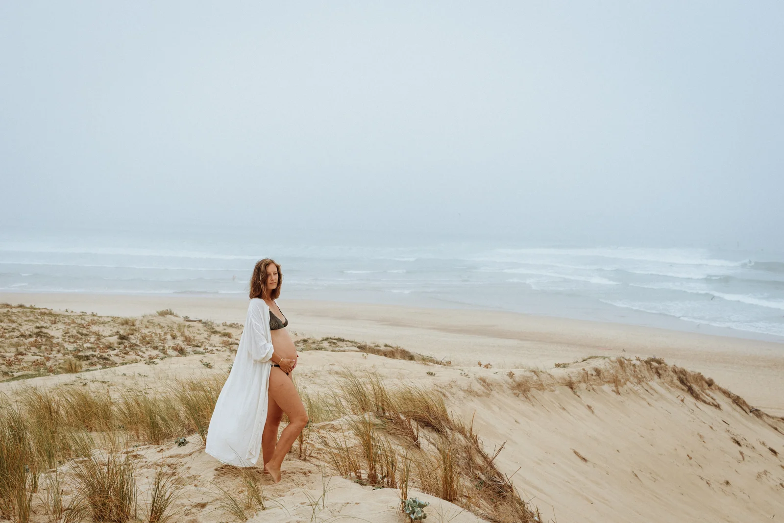 femme enceinte dans les dunes face à l’océan lors d’une séance photo dans les Landes