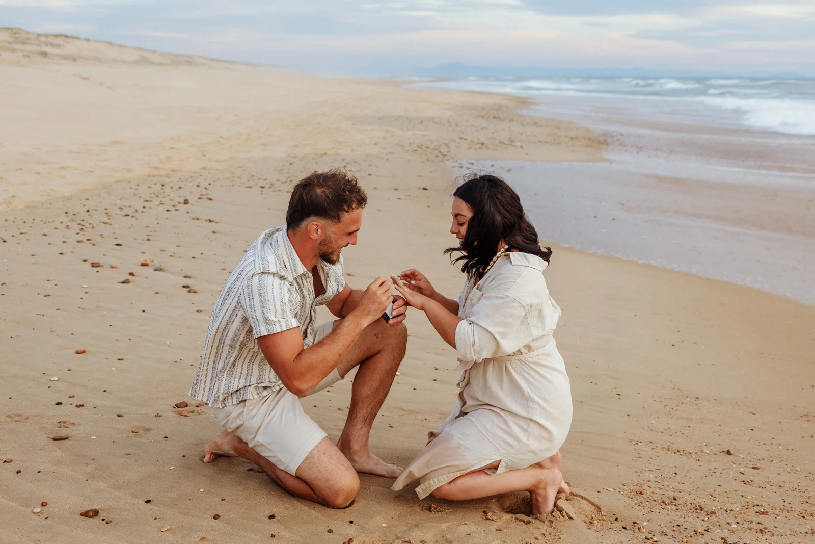 Couple sur la plage au moment où il lui passe la bague après sa demande en mariage à Soustons dans les Landes