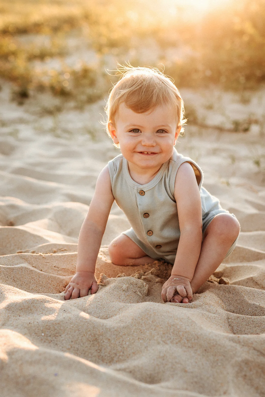 Bébé assis dans le sable au coucher du soleil pendant une séance photo sur la plage dans les Landes
