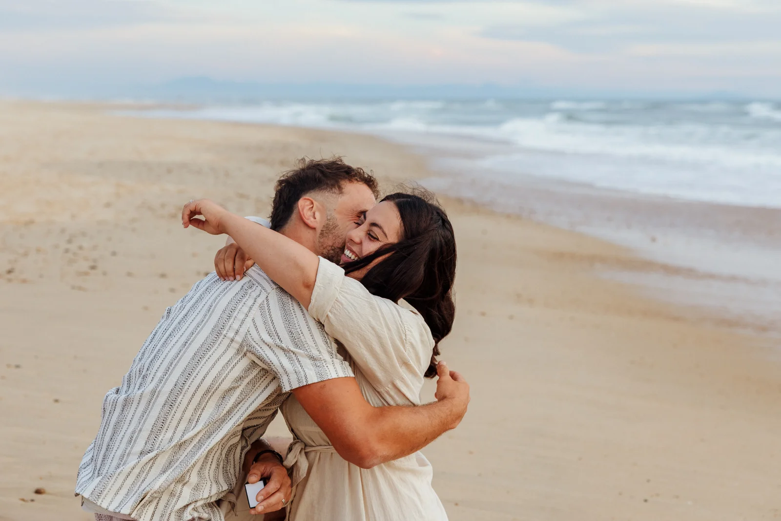 Couple enlacé après une demande en mariage surprise sur la plage dans les Landes