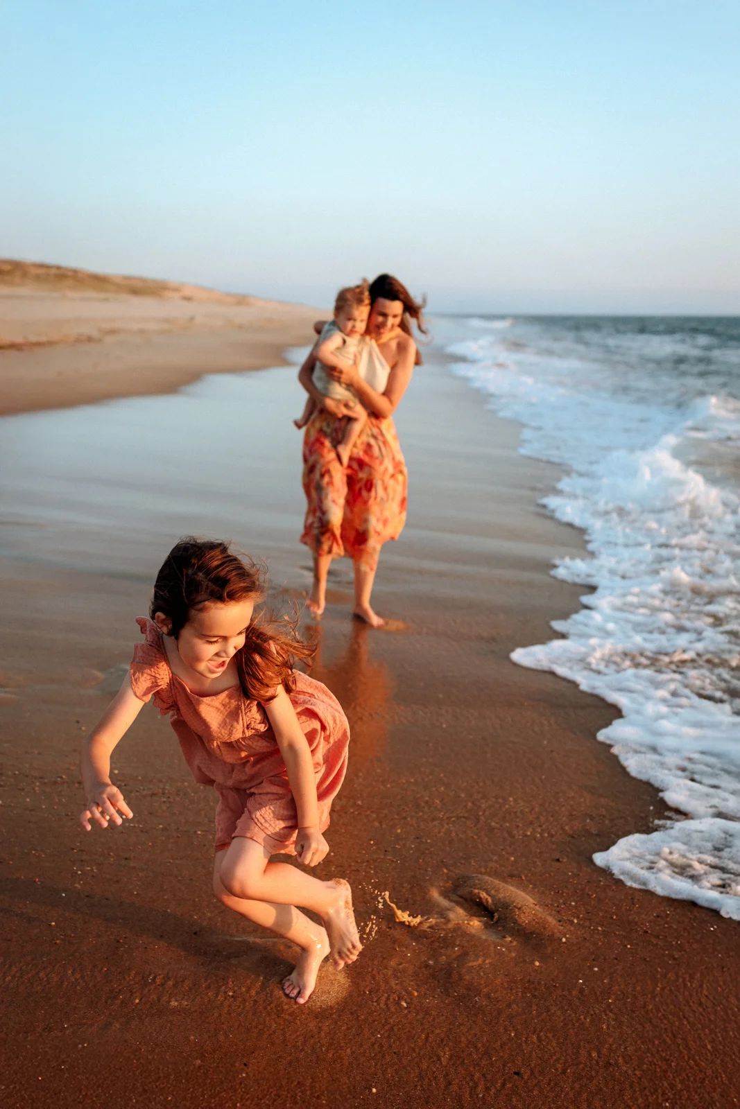 Enfant courant au bord de l’eau au coucher du soleil pendant une séance photo sur la plage dans les Landes