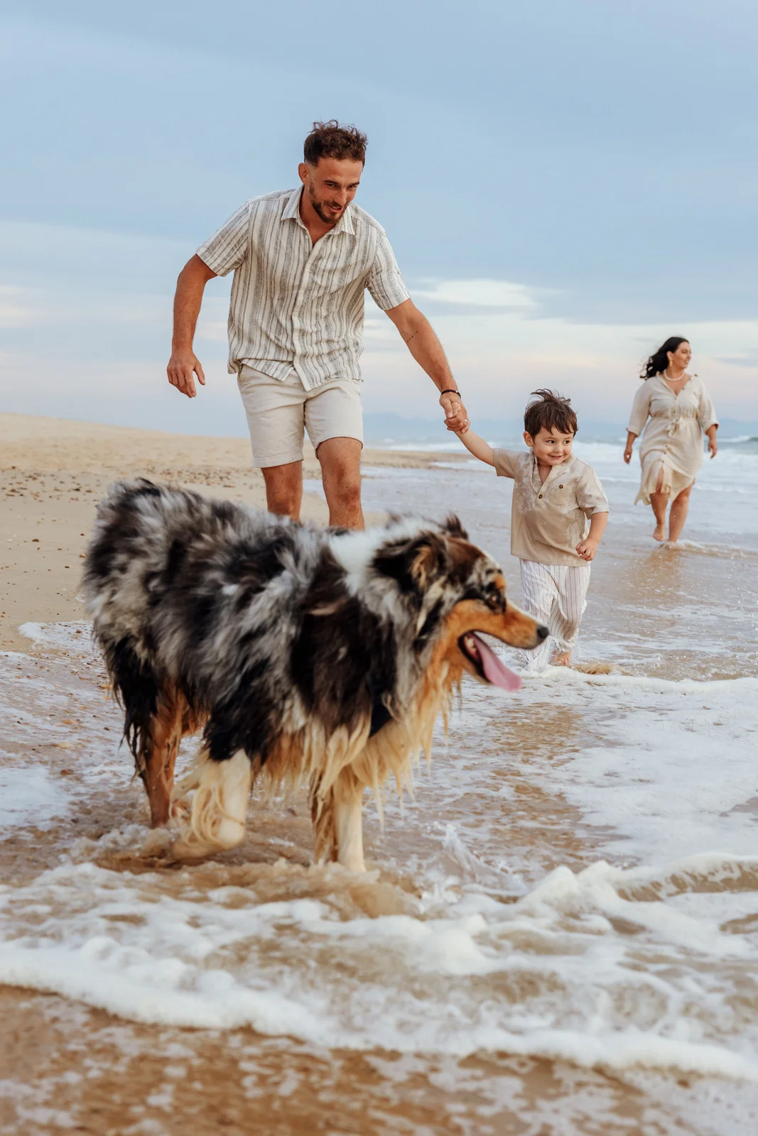 Famille avec leurs deux chiens au bord de l’eau pendant une séance photo sur la plage de Soustons dans les Landes