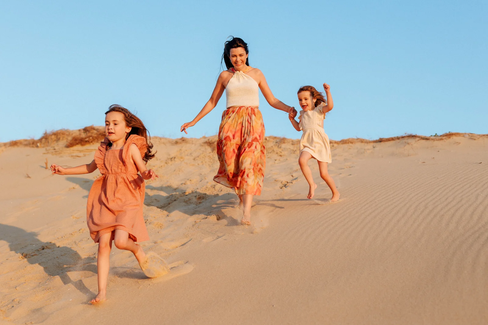Famille courant dans les dunes en fin de journée pendant une séance photo au coucher du soleil dans les Landes