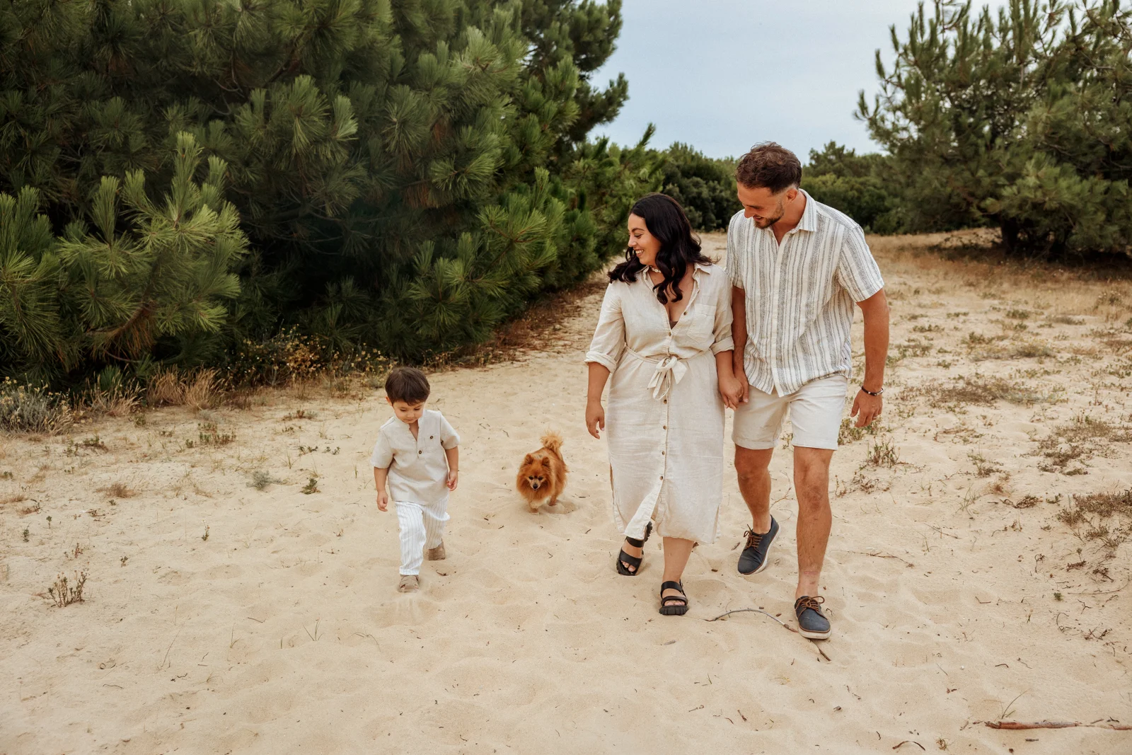 Famille marchant dans le sable avec leur enfant et leur chien pendant une séance photo dans les Landes
