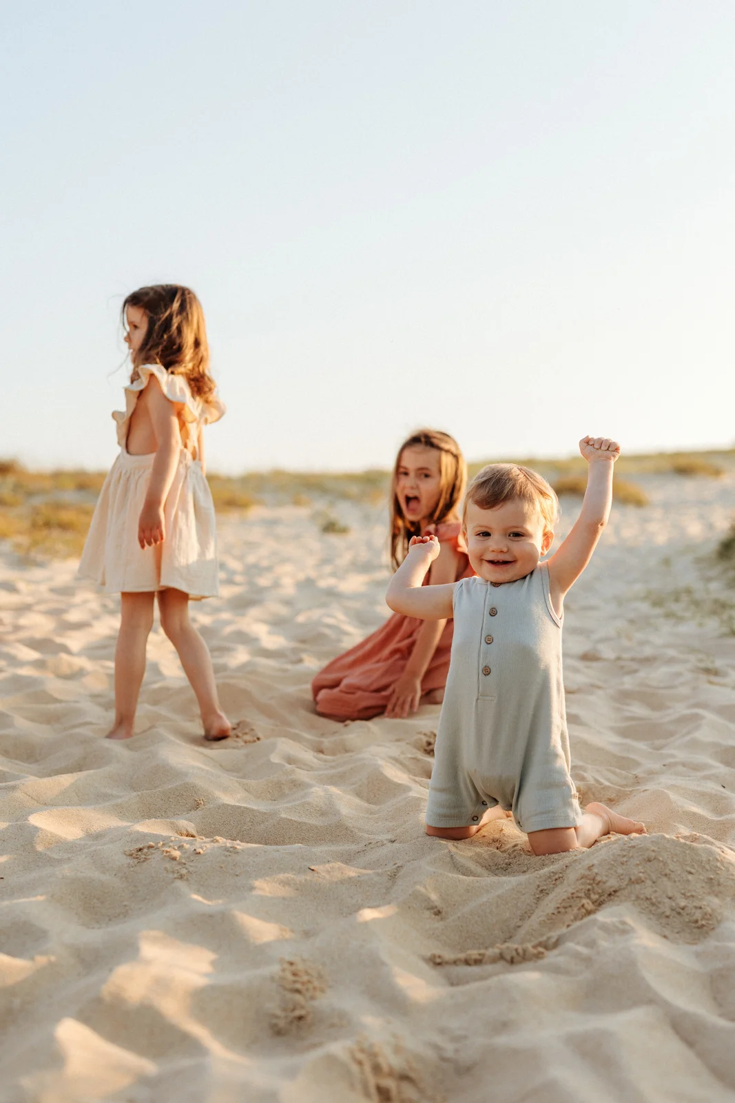Fratrie dans les dunes à la lumière dorée du coucher du soleil pendant une séance photo dans les Landes