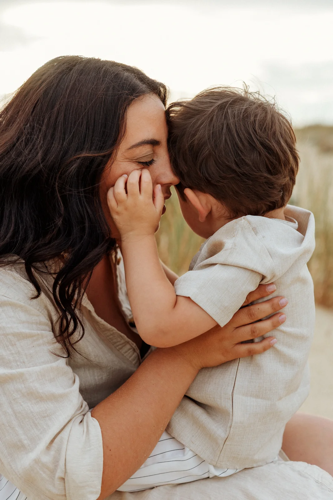 Maman serrant son petit garçon contre elle pendant une séance photo famille sur la plage dans les Landes