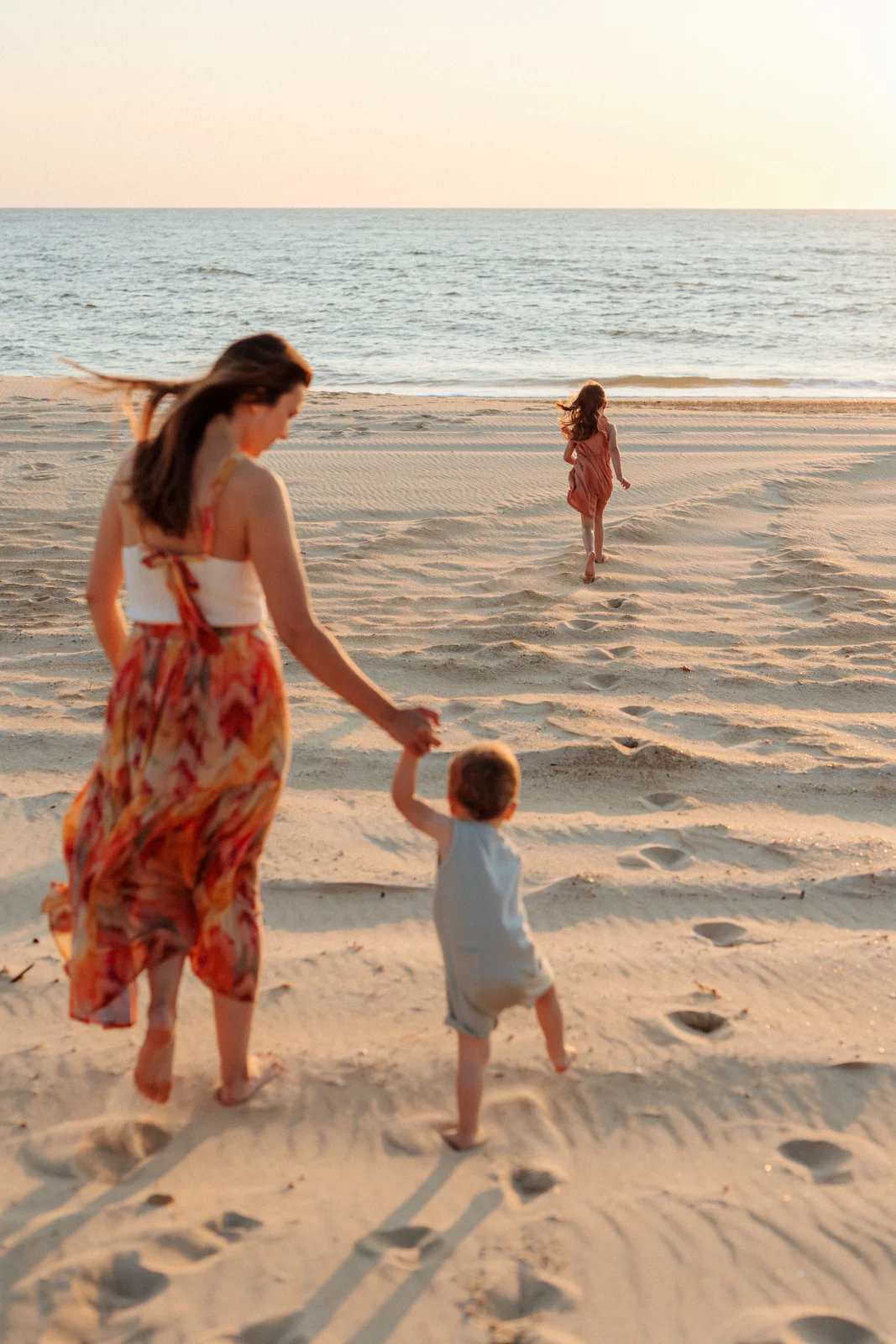 Maman marchant avec son enfant vers la plage en fin de journée pendant une séance photo dans les Landes