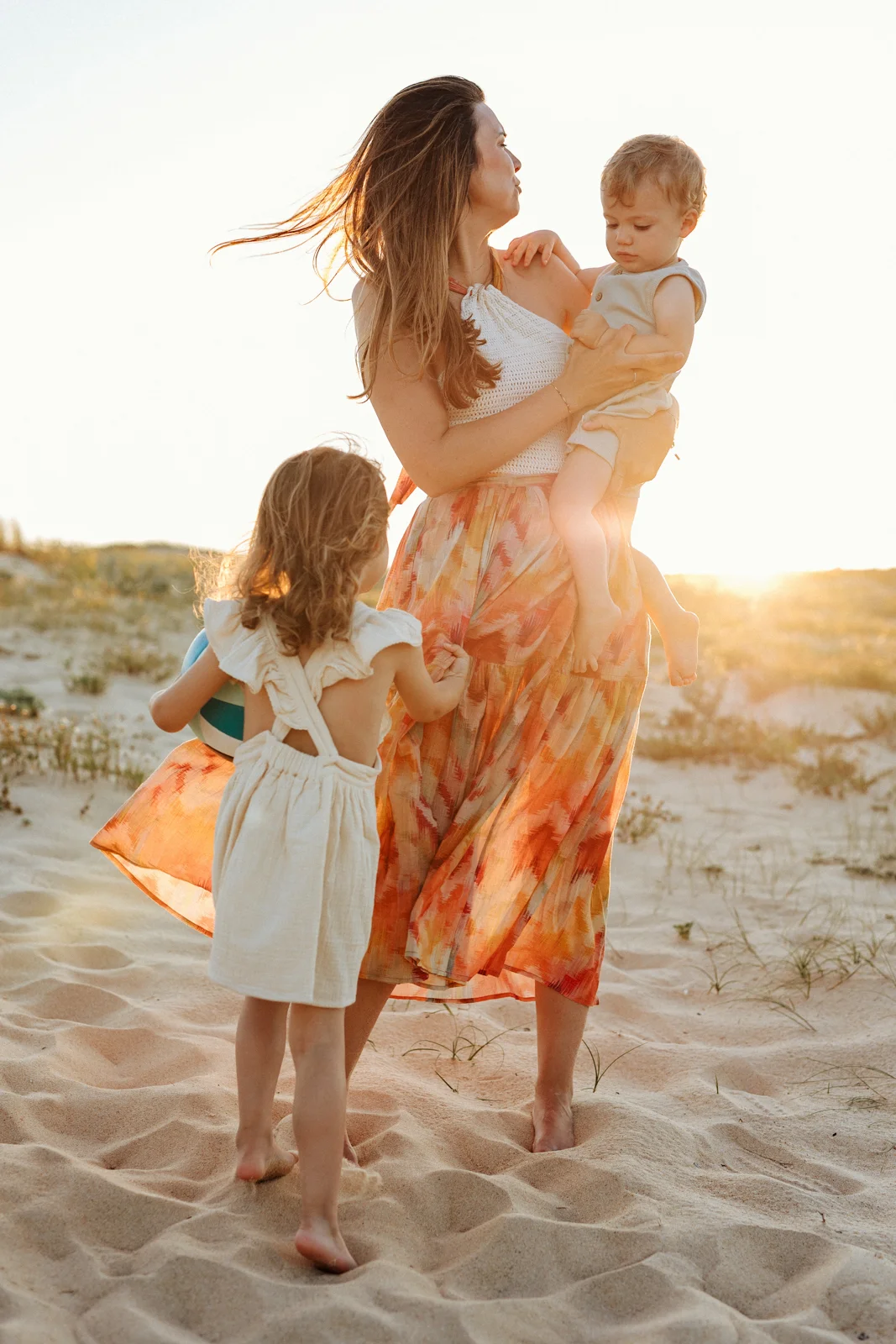 Maman avec ses enfants dans les dunes au coucher du soleil pendant une séance photo dans les Landes