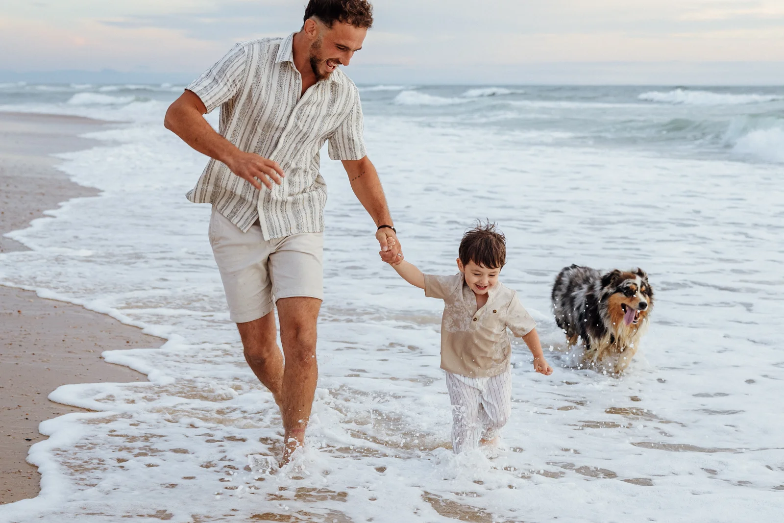 Papa courant avec son fils dans les vagues pendant une séance photo famille à Soustons dans les Landes