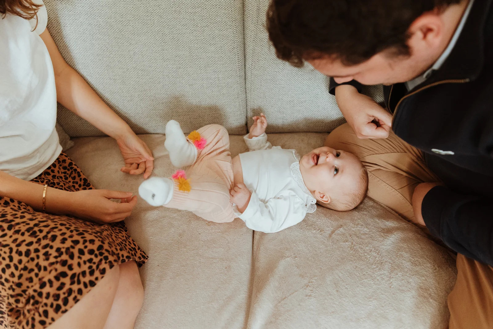 Bébé entouré de ses parents pendant une séance photo famille à domicile