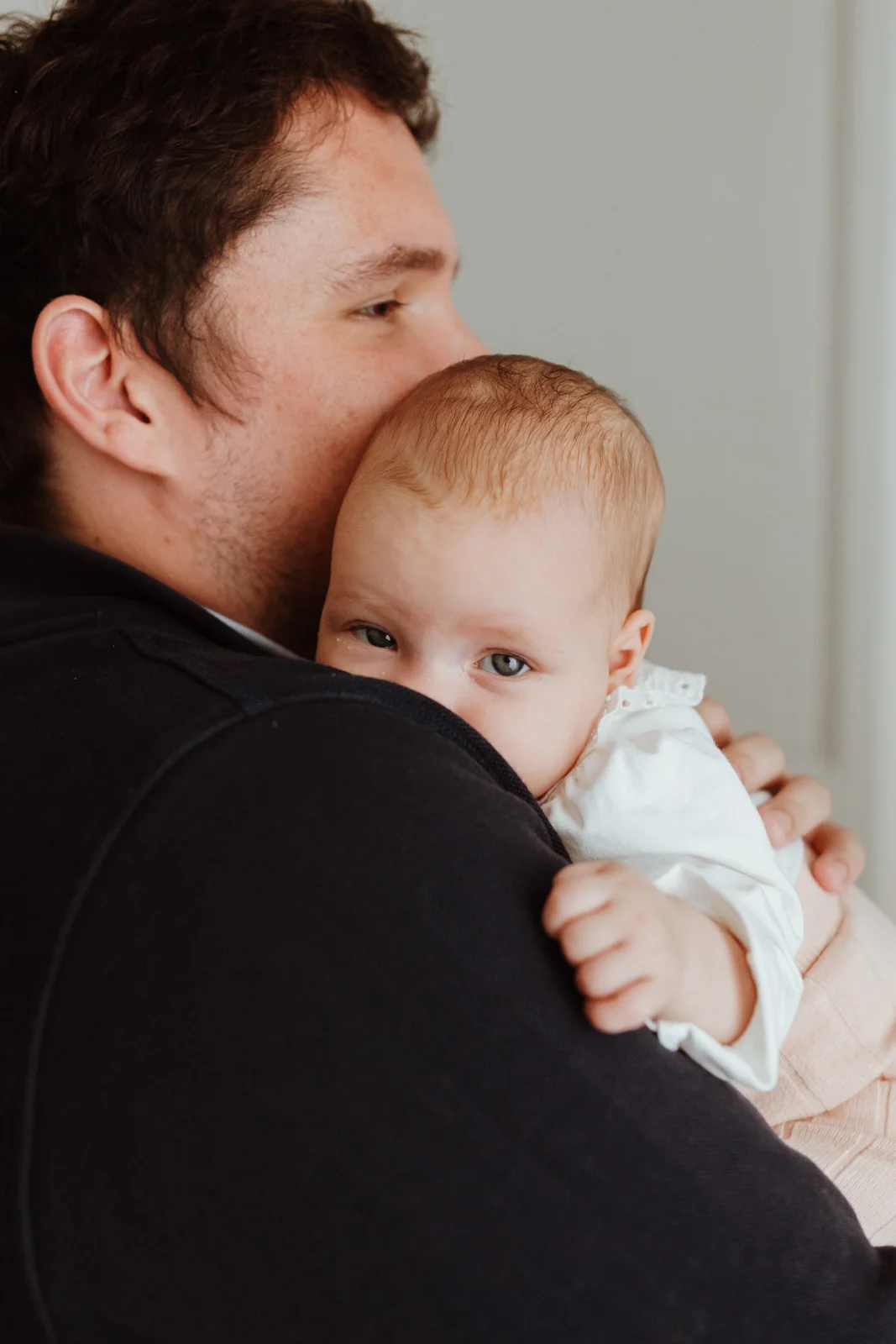 Bébé de 2 mois dans les bras de son papa pendant des photos de famille naturelles