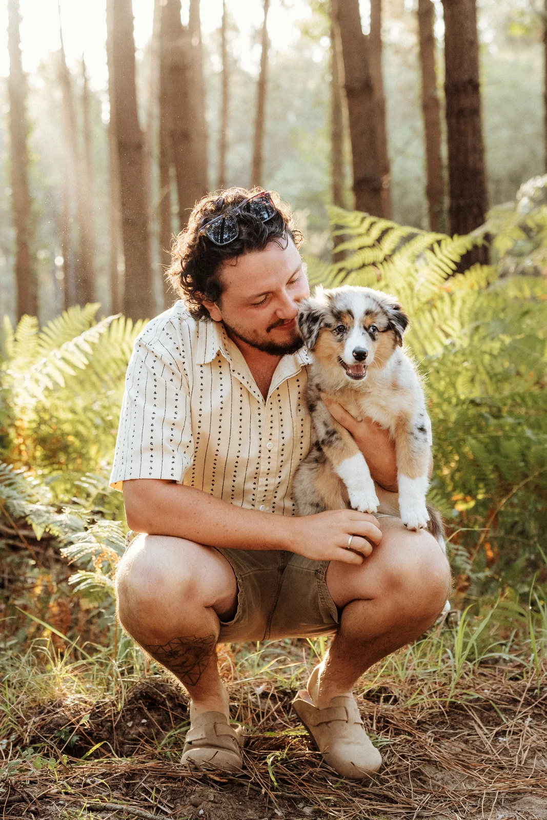 Propriétaire assis avec son chiot berger américain lors d'une séance photo dans les Landes