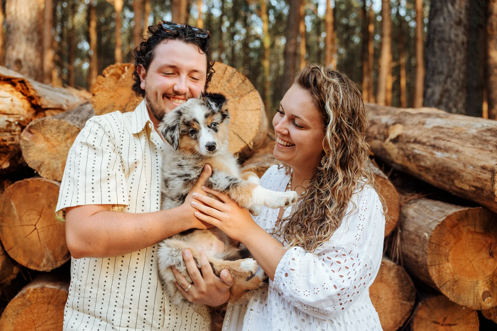 Couple tenant son chiot berger américain dans les bras pendant une séance photo en forêt