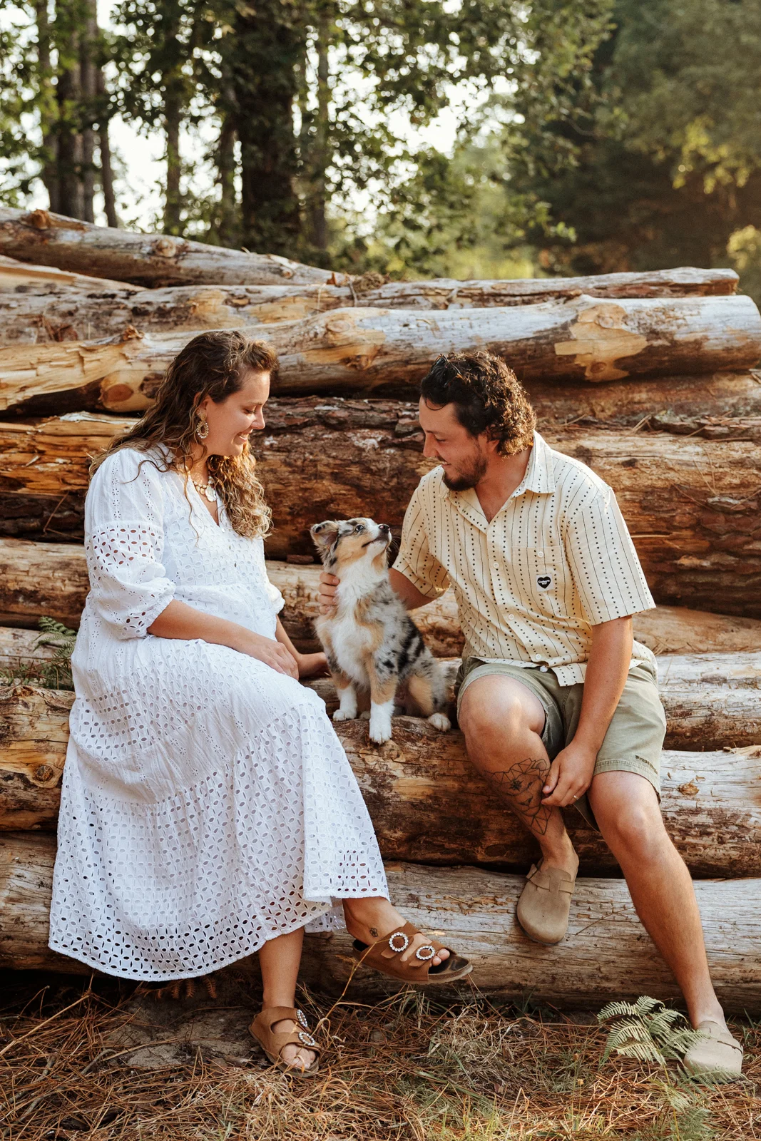 Couple assis avec son chiot berger américain lors d'une balade en forêt dans les Landes