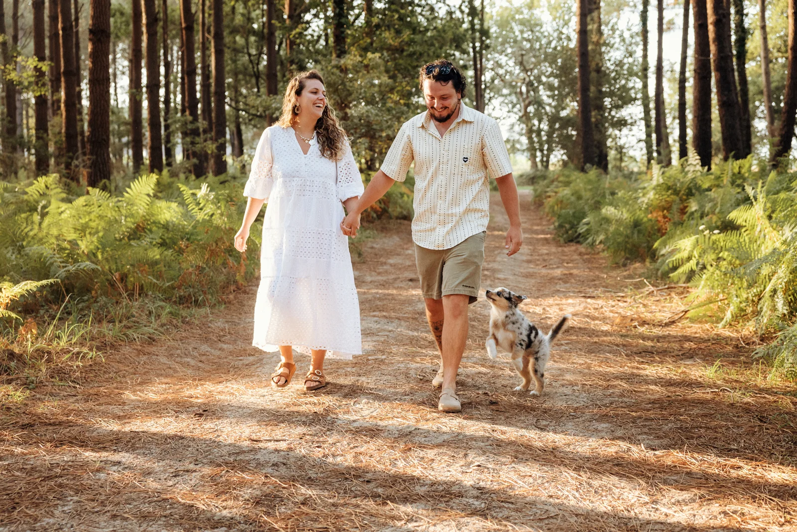 Couple se promenant avec son chiot berger américain dans la forêt des Landes