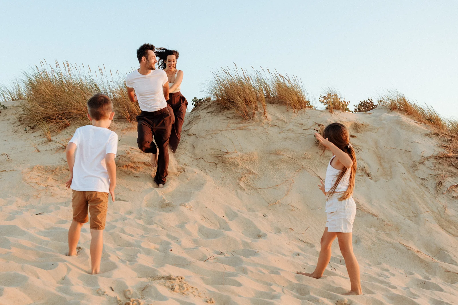 Famille descendant une dune de sable lors d'une séance photo au coucher du soleil