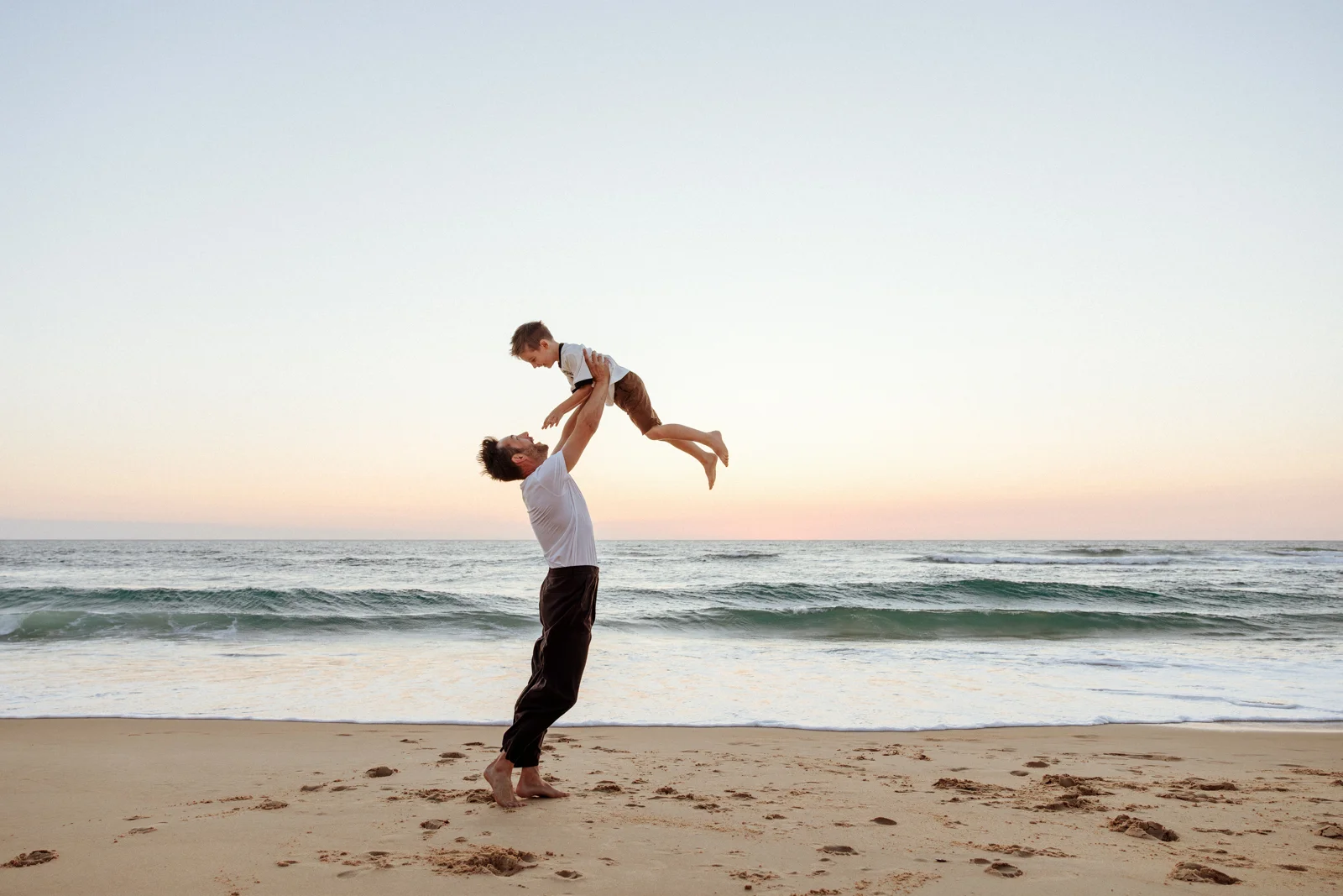 Papa jouant avec son fils sur la plage pendant une séance photo famille