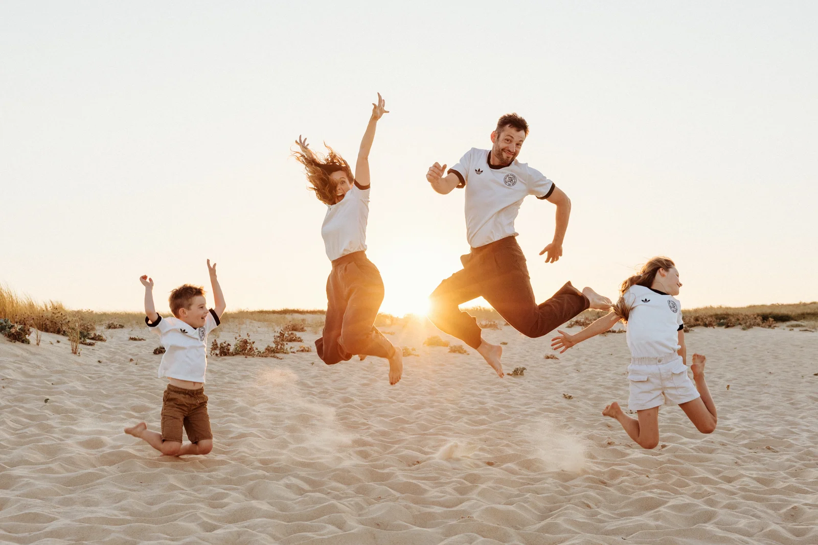 Famille sautant dans les dunes lors d'une séance photo dans les Landes