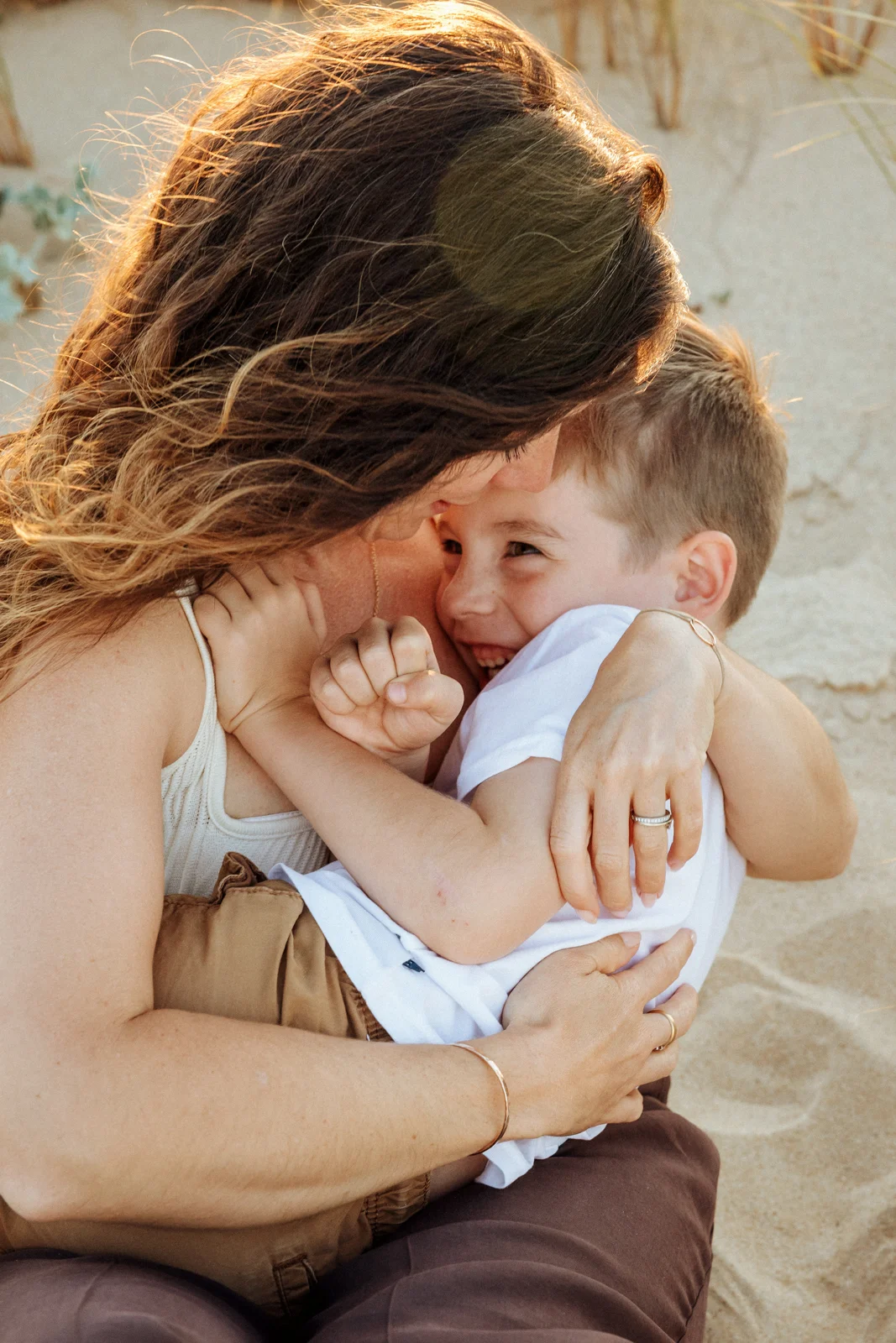 Maman serrant son fils dans ses bras sur une plage des Landes lors d'une séance photo famille