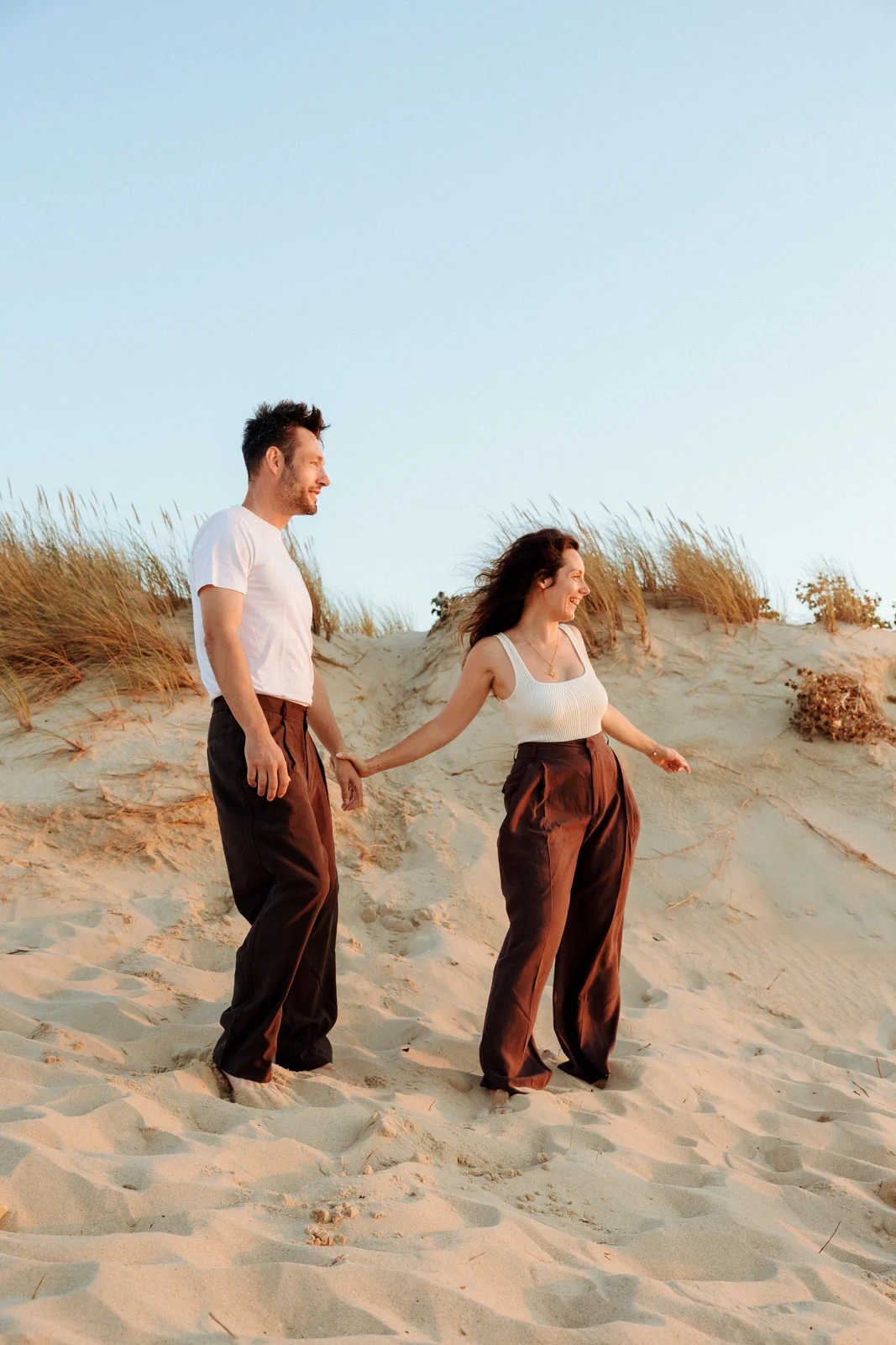 Couple se promenant dans les dunes au coucher du soleil pendant une séance photo dans les Landes