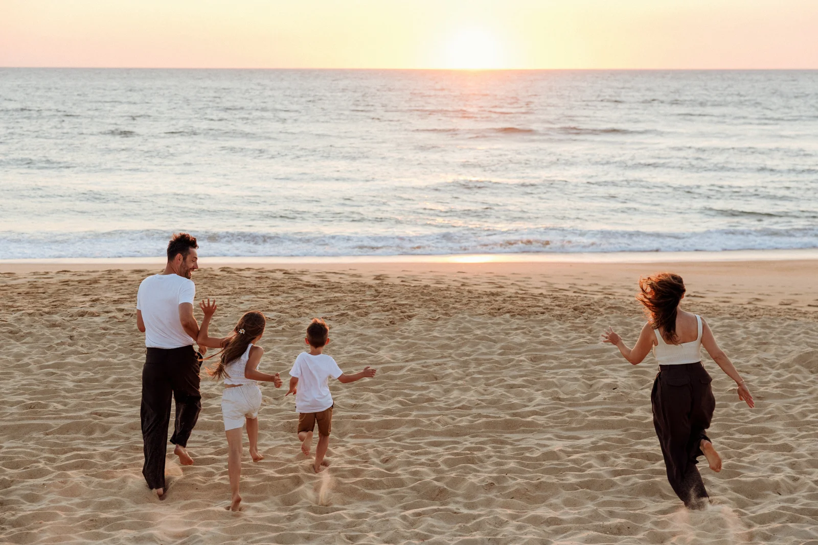 Famille profitant de l'océan au coucher du soleil sur une plage des Landes
