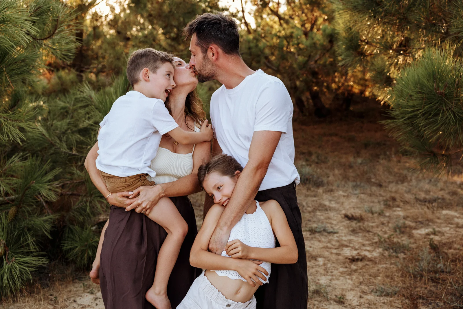 Parents et enfants partageant un moment complice dans les pins lors d'une séance photo famille dans les Landes