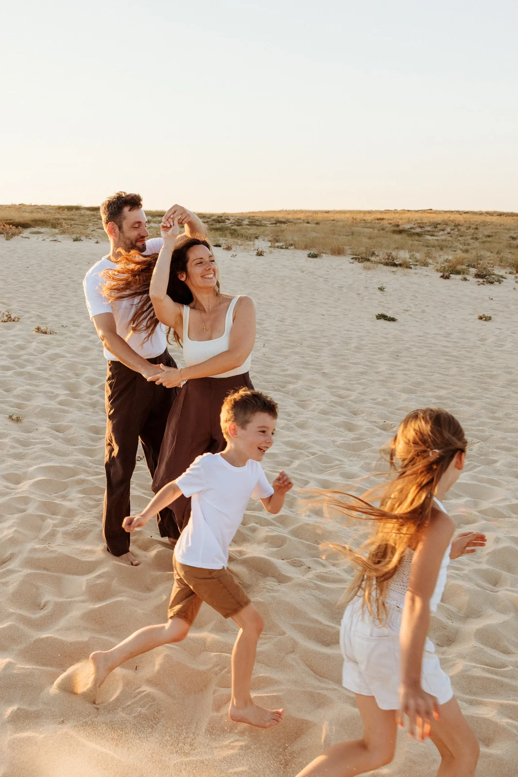 Famille jouant dans le sable au coucher du soleil pendant une séance photo de vacances dans les Landes