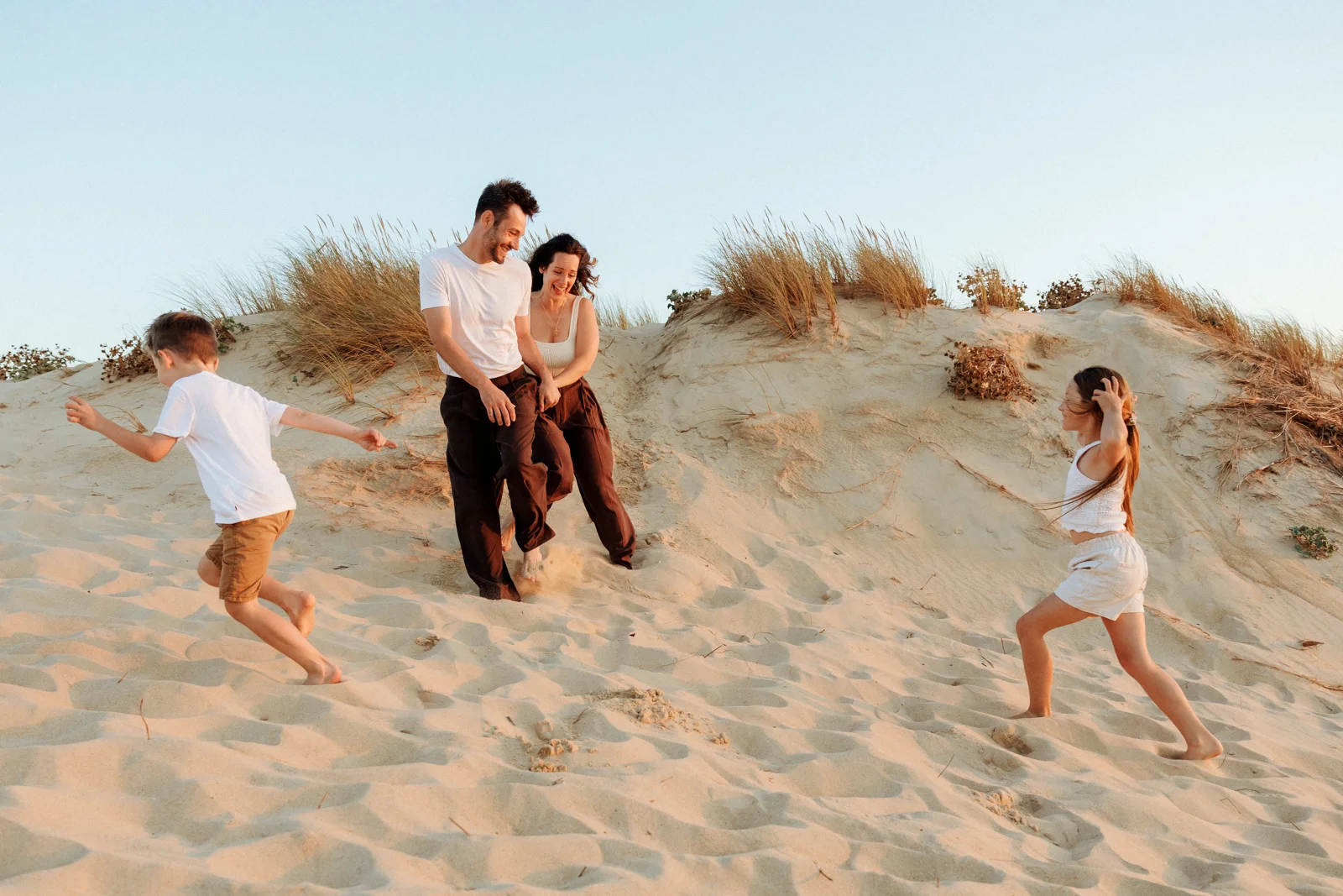 Famille jouant dans les dunes au coucher du soleil pendant une séance photo dans les Landes
