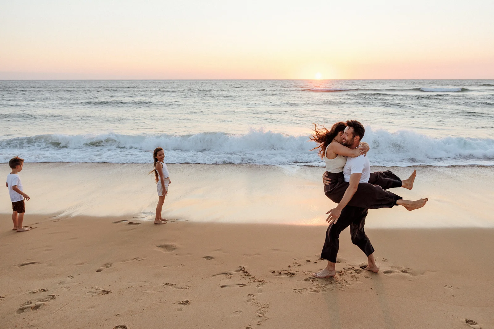 Couple jouant sur la plage au coucher du soleil pendant une séance photo famille dans les Landes