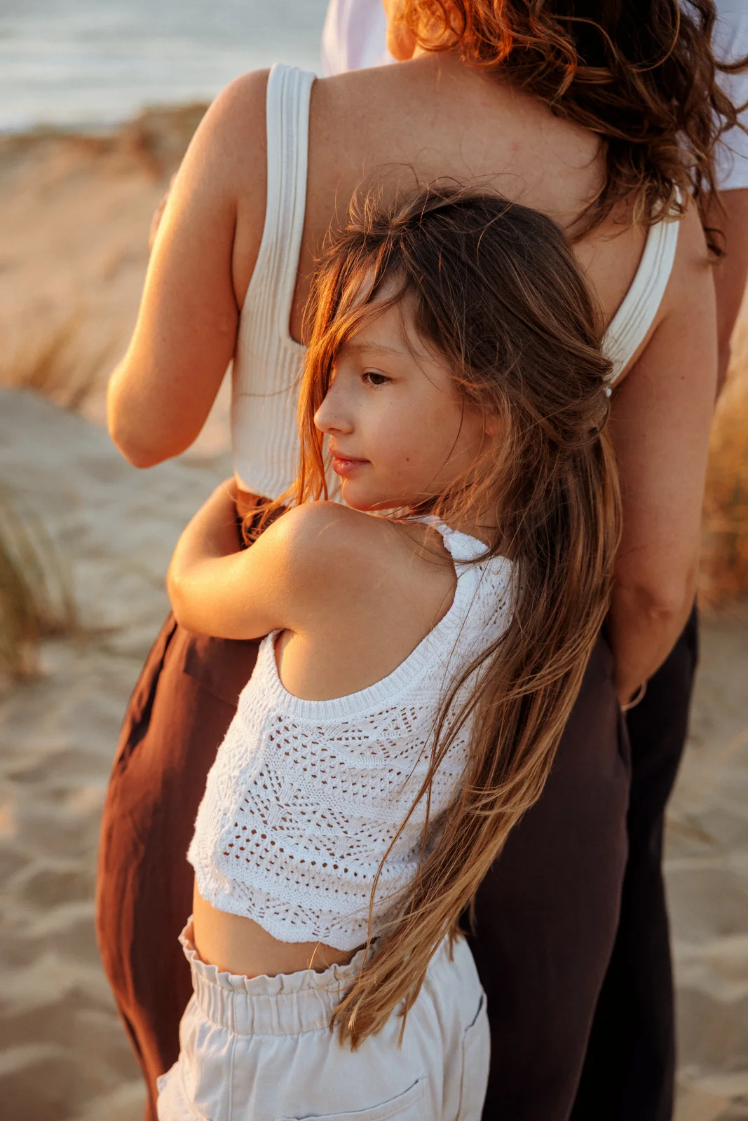 Fillette blottie contre sa maman lors d'une séance photo famille sur la plage dans les Landes